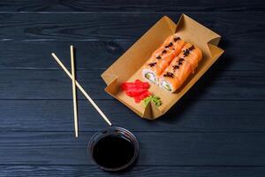 Sushi Entrega serviço. Sushi rolos dentro cartão caixa em Preto fundo. foto