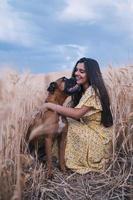 retrato de uma jovem alegre, se divertindo e curtindo a natureza com seu cachorro em um campo de trigo. foto
