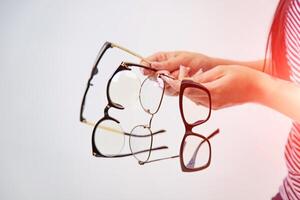 quatro pares do óculos isolado em branco dentro garotas mãos. óculos apresentação. fechar-se foto