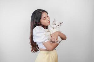 retrato do jovem ásia mulher segurando fofa boneca de pano gato com azul olhos. fêmea abraçando dela fofa grandes cabelo gatinha isolado de branco fundo. adorável doméstico animal conceito. foto