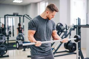 Atlético fisica homem Treinamento dentro a ginástica academia. Forte bonito masculino trabalhando com esporte equipamento. foto