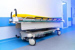 contemporâneo hospital cama em rodas com amarelo colchões dentro luz branco e azul corredor. foto