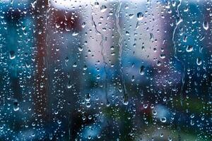 gotas de chuva no vidro da janela. foco seletivo. fundo da cidade chuvosa foto