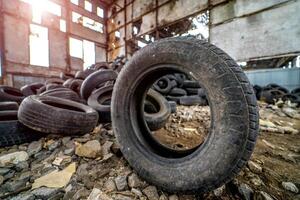 sujo velho pneu é em a terra em pé Próximo para a de outros usava pneus dentro a estragado plantar. borracha lixo a partir de a carro. fechar-se foto
