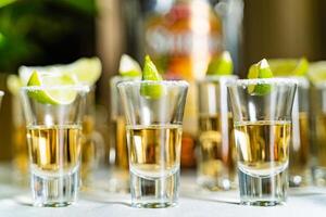 óculos do prata e ouro tequila com Lima e sal em a mesa. álcool dentro curto copos, Lima e sal, tonificado imagem. fechar-se foto