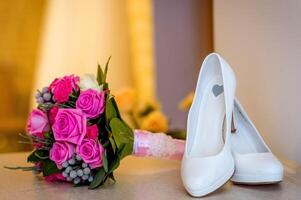 Casamento branco sapatos e ramalhete do Rosa e roxa rosas. nupcial sessão de fotos. fechar-se. foto