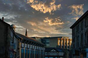 dramático pôr do sol sobre uma pitoresco Cidade rua com histórico edifícios e uma vibrante céu com dourado nuvens dentro Lancastre. foto