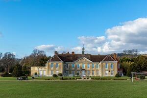 elegante histórico mansão com uma exuberante verde gramado debaixo uma azul céu com espalhados nuvens. foto