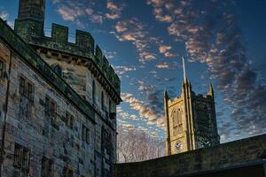 histórico pedra edifícios com torres contra uma dramático céu às crepúsculo dentro Lancastre. foto