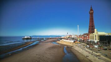 cênico Visão do Blackpool de praia e torre em uma ensolarado dia, com Claro azul céu e calma mar, popular Reino Unido beira-mar destino. foto