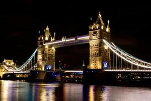 noite Visão do torre ponte dentro Londres com iluminado luzes refletindo em a Tamisa rio. foto