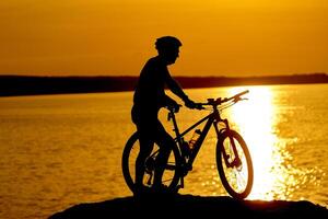 homem ciclismo às de praia em crepúsculo verão temporada. ativo estilo de vida conceito foto