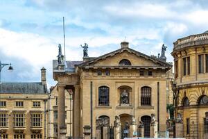 clássico europeu arquitetura com estátuas em a cobertura debaixo uma nublado céu dentro Oxford, Inglaterra. foto