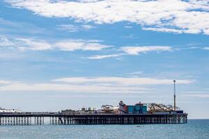 beira-mar cais com diversão parque debaixo uma nublado céu dentro Brighton, Inglaterra. foto