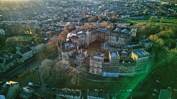 aéreo Visão do uma histórico lancaster castelo às pôr do sol com em torno da vegetação e urbano pano de fundo. foto