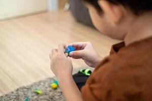 ásia Garoto jogando com plasticina dentro a quarto foto