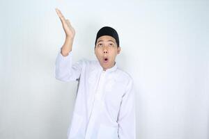 chocado ásia homem muçulmano levantando mão acima para apresentando isolado em branco fundo foto