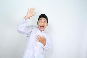engraçado ásia muçulmano homem olhando acima com surpreso expressão e levantando mão para apresentando isolado em branco fundo foto