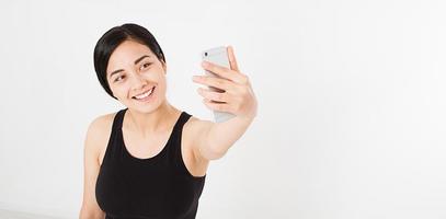 mulher moderna e sexy asiática, coreana, tirando uma selfie isolada no fundo branco, copie o espaço, simule-se foto