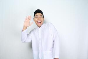 engraçado ásia muçulmano homem mostrar surpreso expressão enquanto acenando mão dizer Olá isolado em branco fundo foto