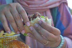 metade comido carne hamburguer em mão foto