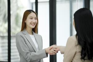 mulheres de negócios aperto de mão selagem uma bem sucedido acordo foto