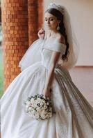 lindo noiva com Casamento flores ramalhete, atraente mulher dentro Casamento vestir. feliz recém-casado mulher. noiva com Casamento Maquiagem e Penteado. sorridente noiva. Casamento dia. linda noiva. casado. foto