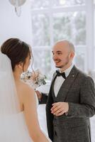 a noiva é vestido dentro a elegante exuberante branco Casamento vestir com uma grandes véu e é pronto para dela noivo. a primeiro encontro do a noiva e noivo foto