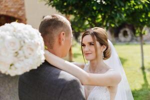 a noiva é vestido dentro a elegante exuberante branco Casamento vestir com uma grandes véu e é pronto para dela noivo. a primeiro encontro do a noiva e noivo foto