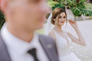 a noiva é vestido dentro a elegante exuberante branco Casamento vestir com uma grandes véu e é pronto para dela noivo. a primeiro encontro do a noiva e noivo foto