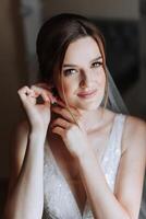 retrato do a noiva dentro a hotel sala. uma lindo jovem menina é vestido dentro uma branco Casamento vestir. moderno Casamento Penteado. natural inventar. foto