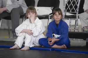 abril 23, 2023. bielorrússia, gomil central estádio. judo crianças. pequeno judo meninas sentar em Esportes tapetes. foto