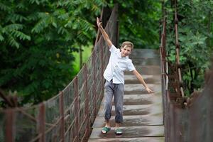 uma criança anda em ao longo uma suspensão ponte sobre uma montanha rio. foto