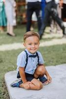 uma pequeno Garoto é jogando dentro a Jardim em uma verão dia. vestir a criança dentro luz roupas, ter Diversão. feliz criança. foto