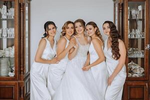 uma lindo noiva e dela damas de honra estão tendo Diversão dentro a manhã. Casamento celebração. feliz meninas às seus melhor amigos casamento. uma lindo e elegante noiva com dela damas de honra foto