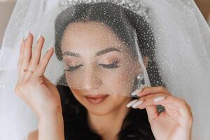 retrato do a noiva dentro a hotel sala. uma lindo jovem menina é vestido dentro uma branco Casamento vestir. moderno Casamento Penteado. natural inventar. foto