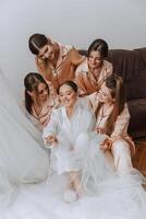 uma lindo noiva e dela damas de honra estão tendo Diversão dentro a manhã. Casamento celebração. feliz meninas às seus melhor amigos casamento. uma lindo e elegante noiva com dela damas de honra foto