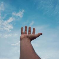 homem mão gesticulando em a azul céu foto