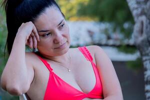 latim mulher dentro uma roupa de banho olhando para a piscina a partir de uma cadeira. foto