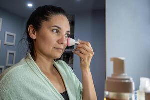 latim mulher usando uma facial Maquiagem escovar. foto