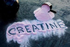 a palavra creatina escrito em derramado morango creatina em uma Preto mesa. Academia e bem estar conceito composição. foto