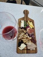 uma vidro do vinho com a sortido queijo prato servido dentro uma adega dentro Napa Califórnia foto