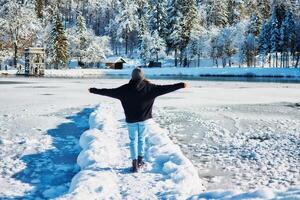 menina jogar com neve de a lago dentro frente do montanhas foto