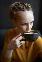 retrato do uma à moda meia idade mulher dentro uma amarelo suéter bebendo café dentro uma cafeteria foto