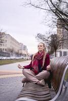 uma meia idade mulher medita em uma Banco dentro uma Primavera rua foto