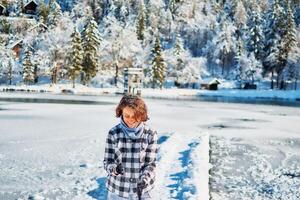 menina jogar com neve de a lago dentro frente do montanhas foto