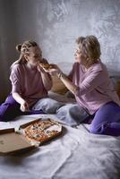 velho mãe e meia idade filha comendo pizza e assistindo uma filme às casa foto