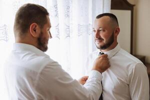 à moda noivo rindo e tendo Diversão com padrinhos enquanto obtendo pronto dentro a manhã para Casamento cerimônia. luxo homem foto