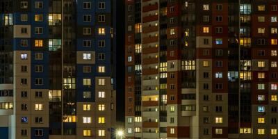 com luz dentro janelas do multistory edifícios às noite. vida dentro uma grande cidade. serenata do luz foto
