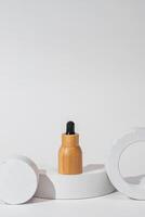 em branco bambu essencial óleo garrafa com pipeta em branco fundo dentro concreto pódio. pele Cuidado conceito com natural cosméticos foto